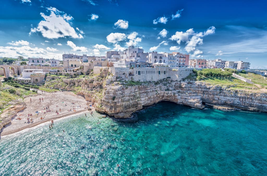 Atemberaubende Klippen und türkisfarbenes Meer bei Polignano a Mare, Apulien: Die charmante Küstenstadt mit ihren weiß getünchten Gebäuden, die sich malerisch an die felsige Küste schmiegen und einen atemberaubenden Blick auf das azurblaue Mittelmeer bieten.